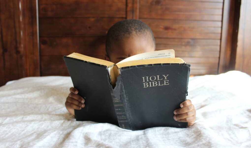 photo of child reading holy bible