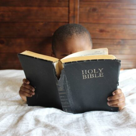 photo of child reading holy bible