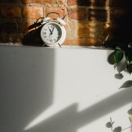 alarm clock on white cupboard near brick wall