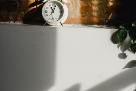 alarm clock on white cupboard near brick wall